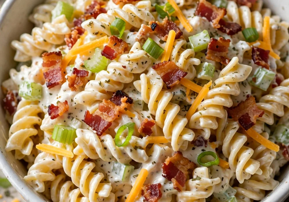 Close-up of classic Italian pasta salad with tri-color rotini, cherry tomatoes, mozzarella pearls, and black olives in a white bowl